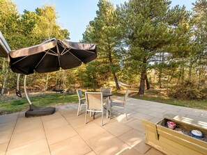 Une terrasse extérieure avec une table et des chaises, une balançoire et un espace salon abrité.
