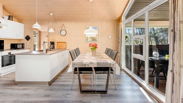 Una cocina moderna con una isla central, iluminación colgante y un amplio ventanal.