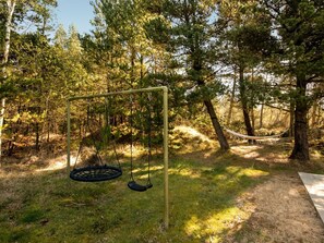 Un ensemble de balançoires installé dans un espace boisé, avec un hamac.