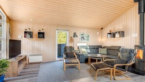 Una sala de estar acogedora con chimenea, un sofá, dos sillones, una mesita de centro y un televisor.