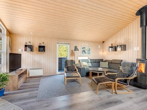 Ein gemütliches Wohnzimmer mit Kamin, einer Couch, zwei Sesseln, einem Couchtisch und einem Fernseher.