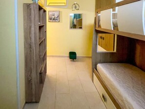A bunk bed room with a wooden headboard, a small stool, and a framed picture on the wall. - FranSea House - Otranto (Otranto)