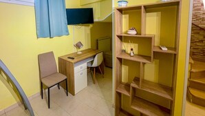 Una habitación con escritorio, silla, televisor y una estantería de madera.