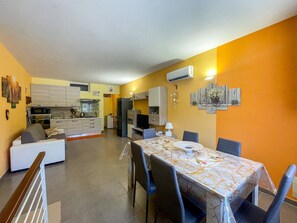 A modern kitchen with white cabinets, a dining area with a table and chairs, and a sofa. - FranSea House - Otranto (Otranto)