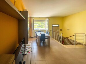 Ein Essbereich mit Tisch und Stühlen, eine Treppe mit Geländer und ein Fenster mit Vorhängen.