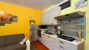 Una cocina compacta con sofá, microondas, estufa y lavabo.