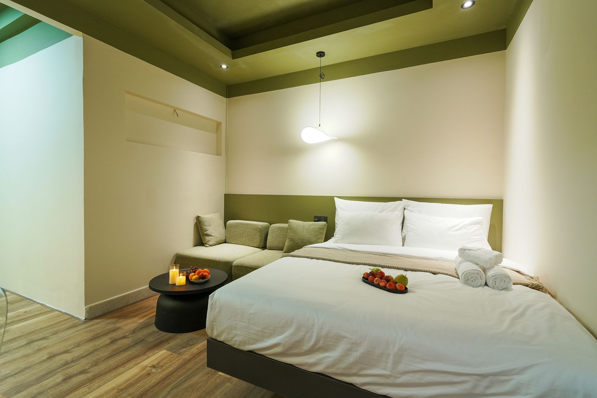 Ein Hotelzimmer mit einem Bett, einem Nachttisch und einem kleinen runden Tisch mit Kerzen und Früchten.