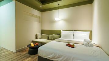 Ein Hotelzimmer mit einem Bett, einem Nachttisch und einem kleinen runden Tisch mit Kerzen und Früchten.