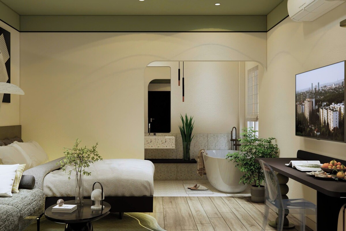 Een moderne hotelkamer met een bed, zithoek en een ruime badkuip.