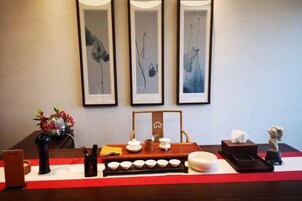 Un mostrador de recepción con obras de arte enmarcadas, un florero con flores y una bandeja con vajilla de té.
