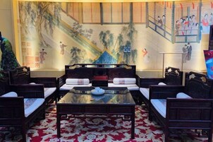 Habitación de estilo tradicional con un mural grande, una mesa central y disposición de asientos.