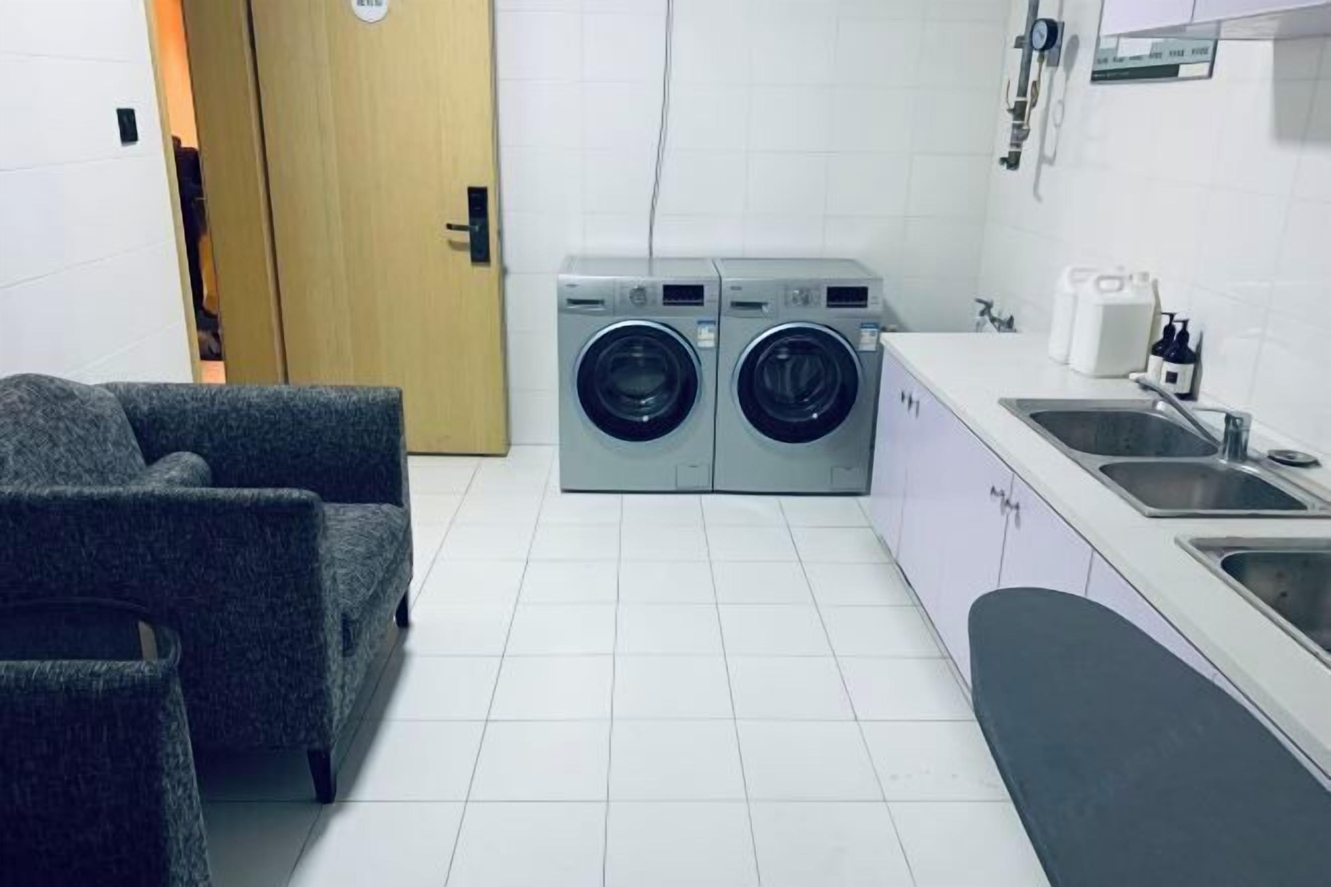 A compact kitchen with a washing machine, a sink, and a chair.