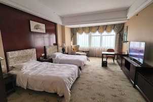Habitación de hotel con dos camas, un televisor, un escritorio y una silla.