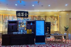 Un hall de hotel con mostrador de recepción, pantalla digital y zona de estar.