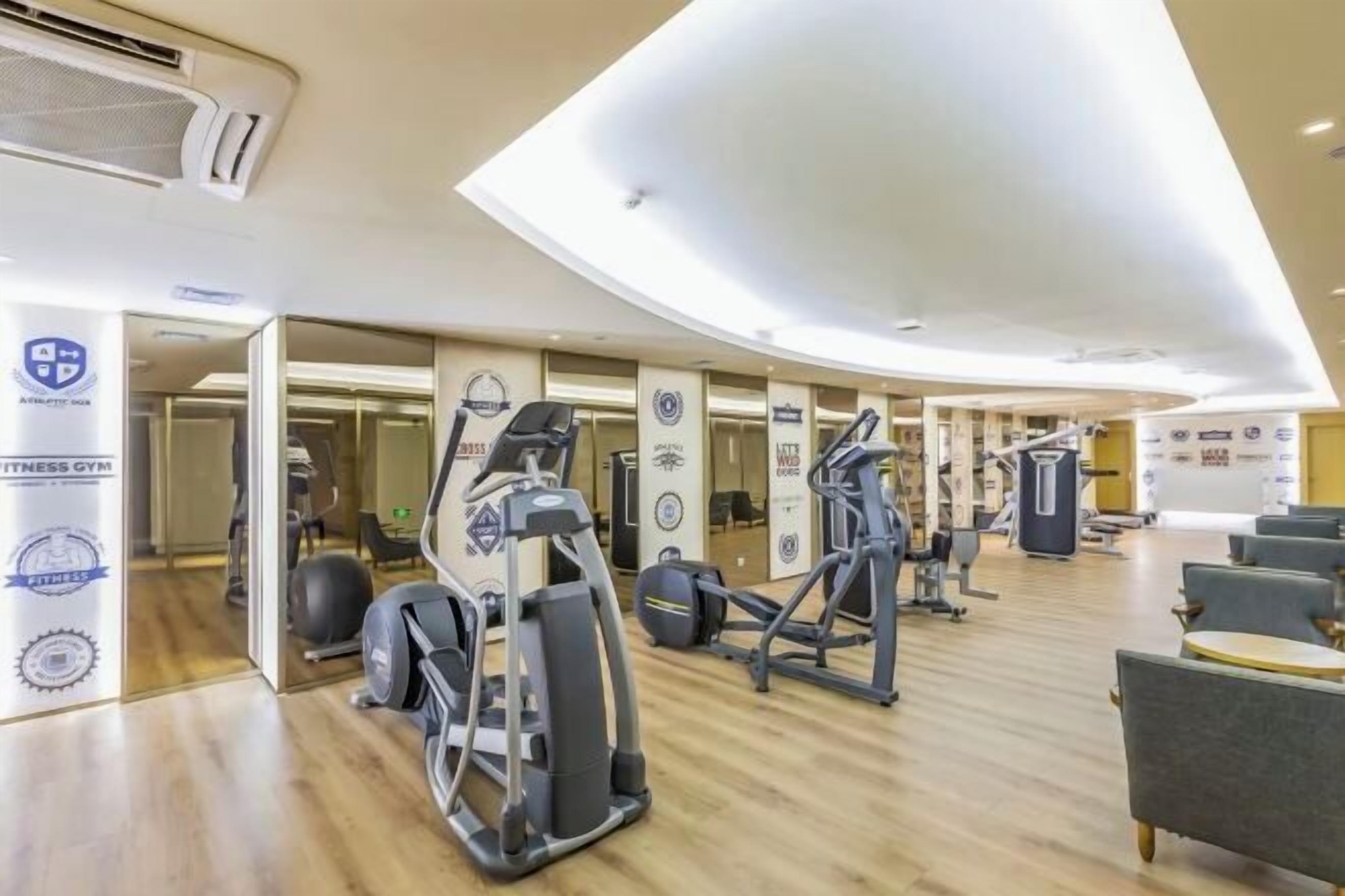 A gym with cardio equipment, weight machines, and a mirrored wall.