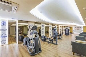 Un gimnasio con equipo cardiovascular, máquinas de pesas y un espejo grande.