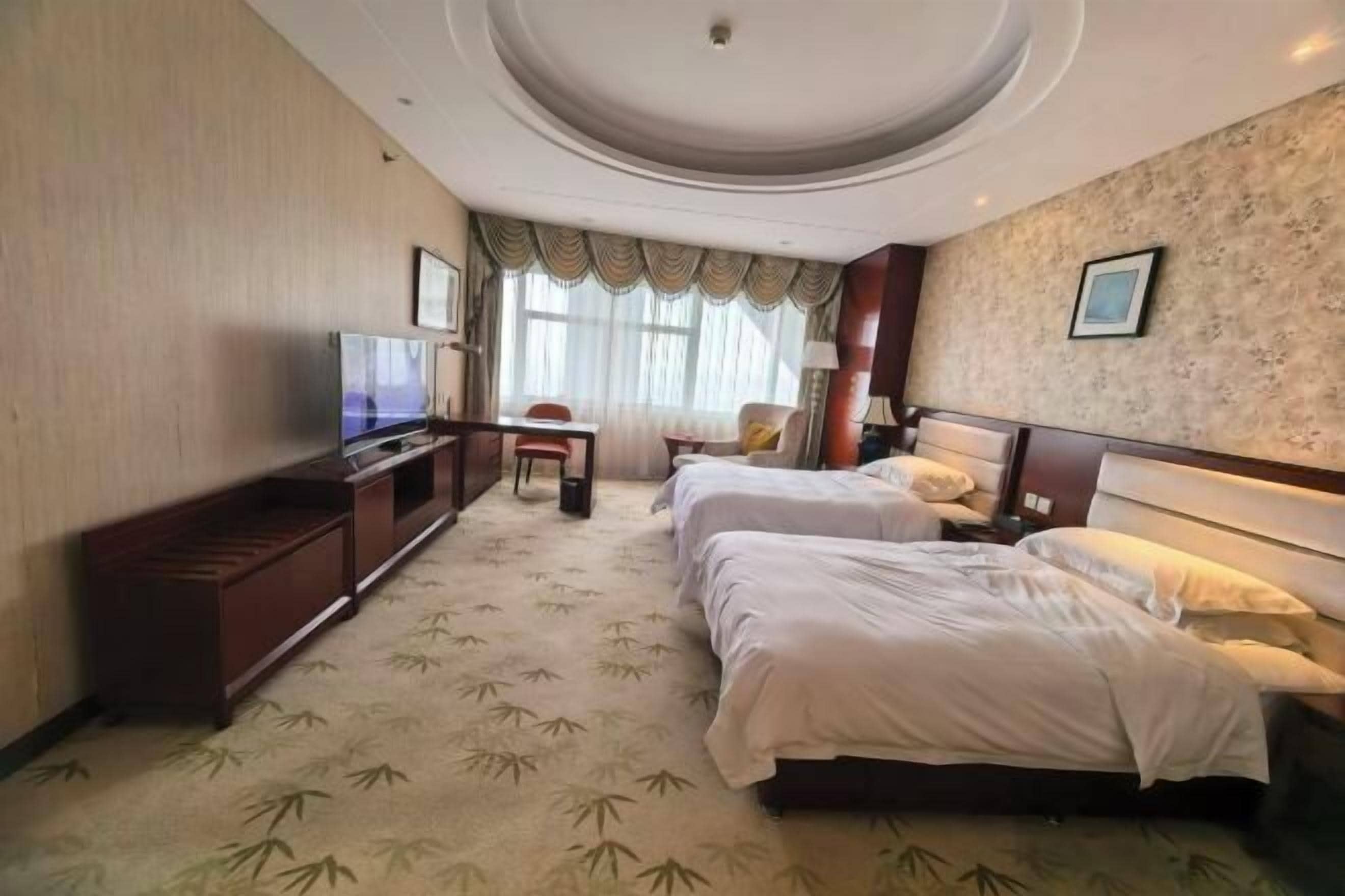 A hotel room with two beds, a TV, a desk, and a chair.