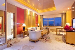 Una habitación de hotel con un ventanal grande, un sofá, un escritorio y una lámpara.