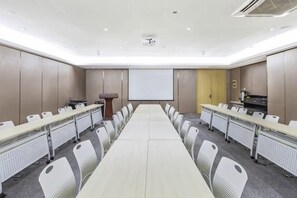 Un salón de conferencias con una larga mesa, sillas, un atril y una pantalla de proyección.