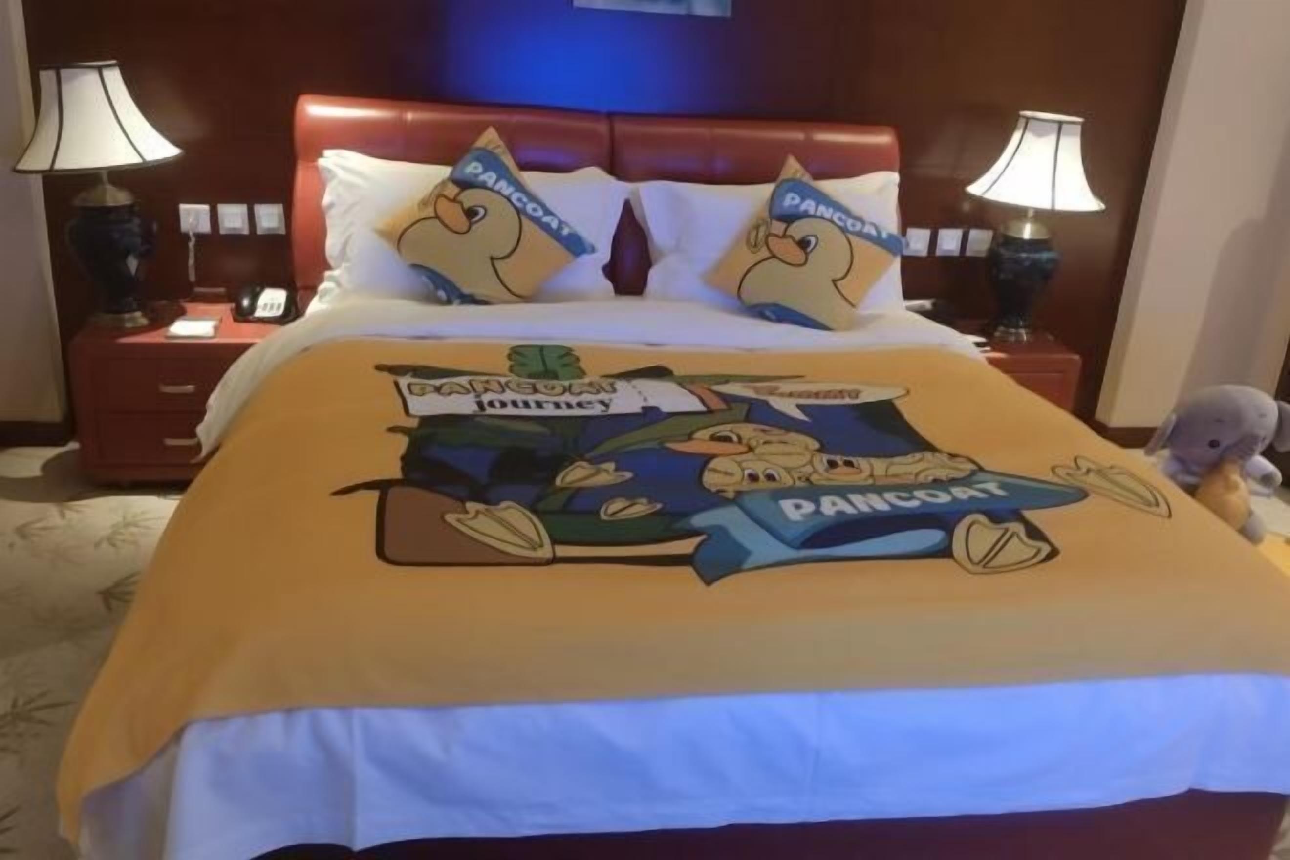 A hotel room with a bed, two nightstands, lamps, and a plush toy on the bed.