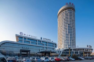 Un hotel con un edificio moderno y una torre cilíndrica alta.