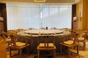 Un salón de conferencias con una mesa redonda, sillas y un amplio ventanal con cortinas traslúcidas.