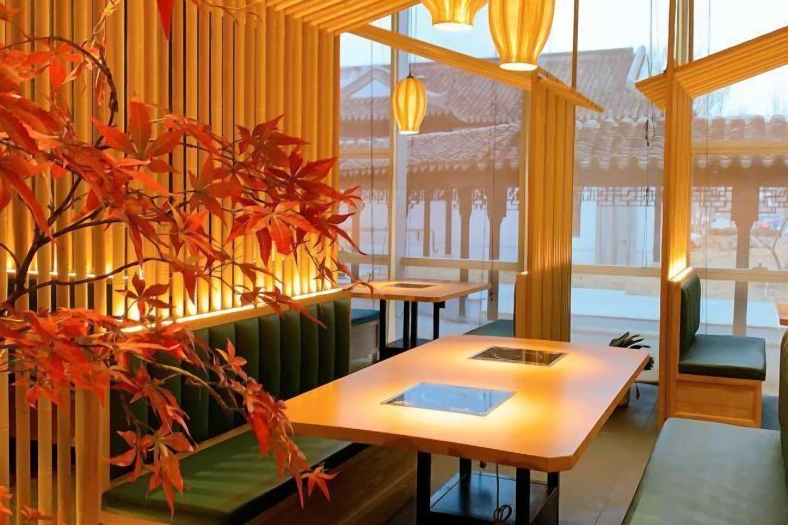 A traditional Japanese-style room with tatami flooring, a low table, and a view of a traditional building outside.