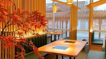 A traditional Japanese-style room with tatami flooring, a low table, and a view of a traditional building outside.
