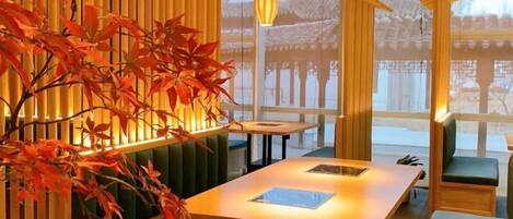 A traditional Japanese-style room with tatami flooring, a low table, and a view of a traditional building outside.
