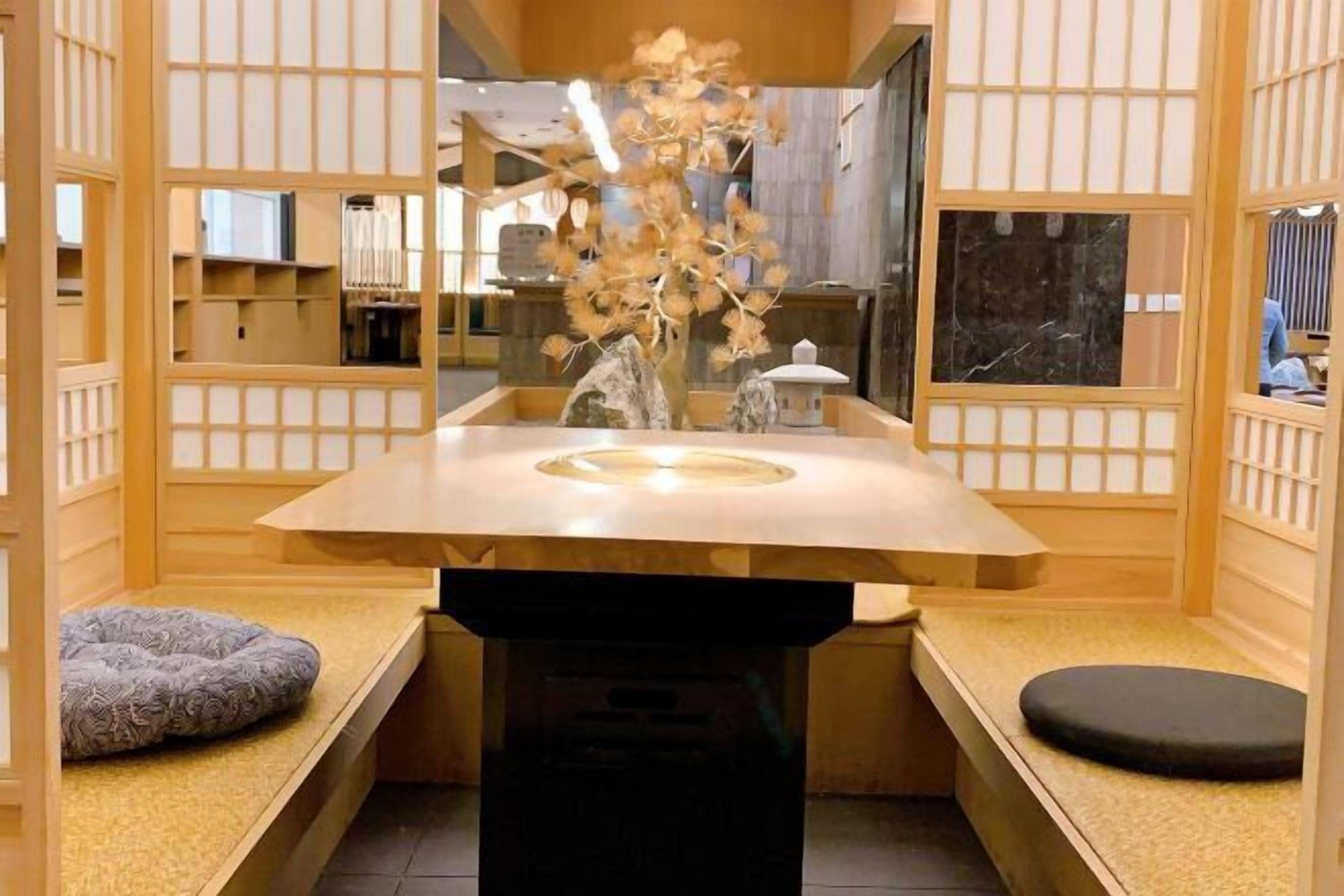 A traditional Japanese-style room with tatami flooring, a low table with a vase of flowers, and a sliding door.