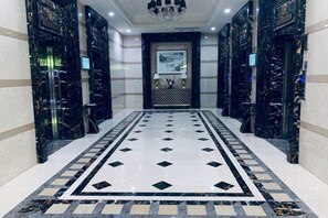 Un vestíbulo de hotel con piso de mármol, un candelabro y un mostrador de recepción.