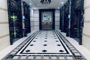 Un vestíbulo de hotel con piso de mármol, un candelabro y un mostrador de recepción.