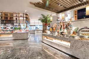 Un moderno vestíbulo de hotel con suelo de mármol, una recepción central y diversos elementos decorativos y plantas.