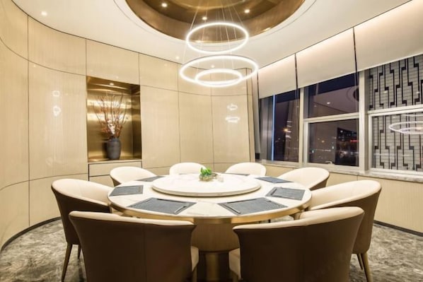 A conference room with a round table, six chairs, and a view of the city at night.