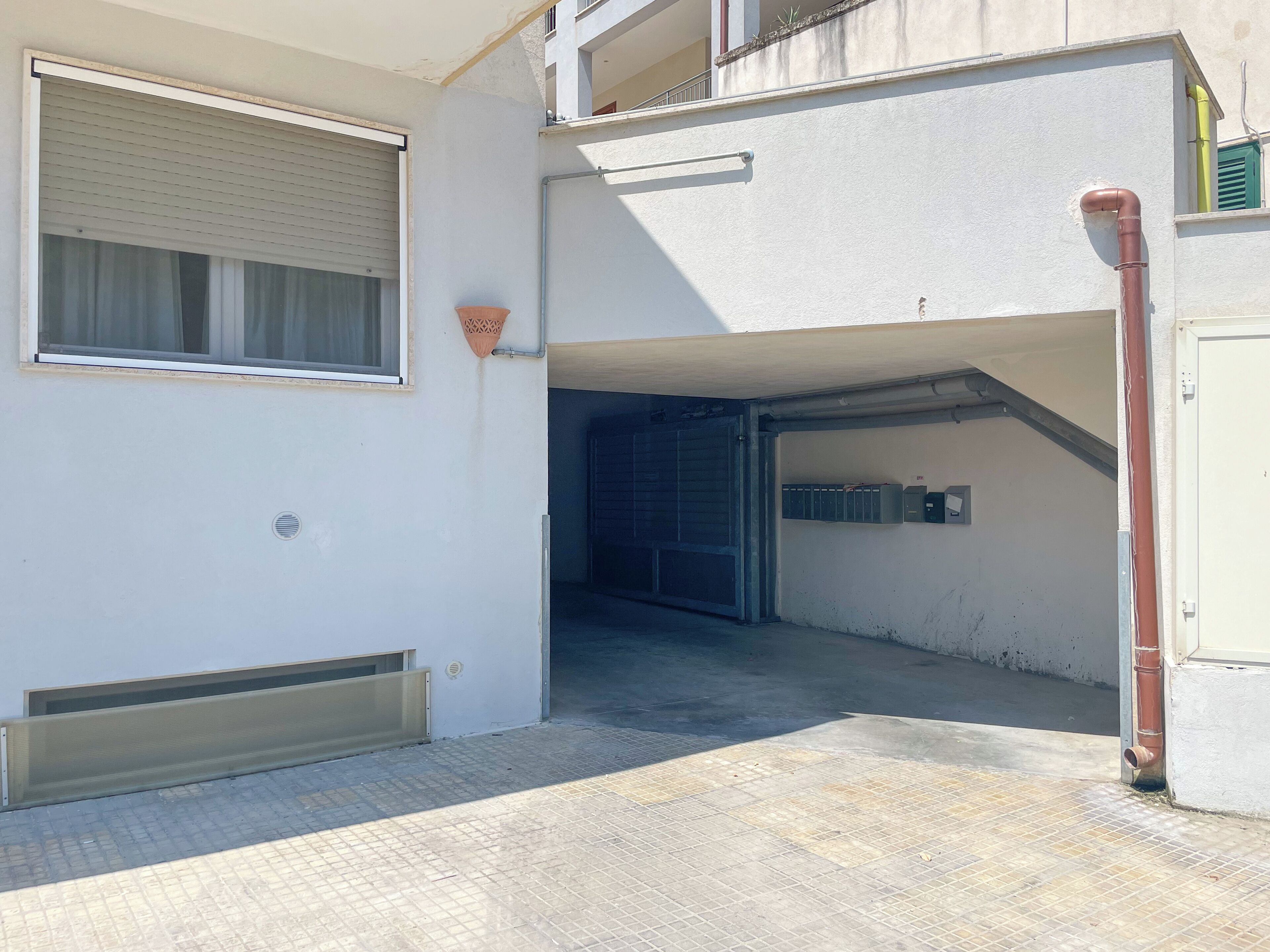 Un bâtiment doté d’une entrée de garage, d’une fenêtre avec des stores et d’une unité de ventilation.