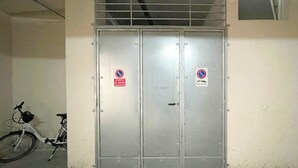 A metal double door with two signs, one indicating no parking and the other no parking for cars. A bicycle is parked to the left of the door. - FranSea House (Otranto)
