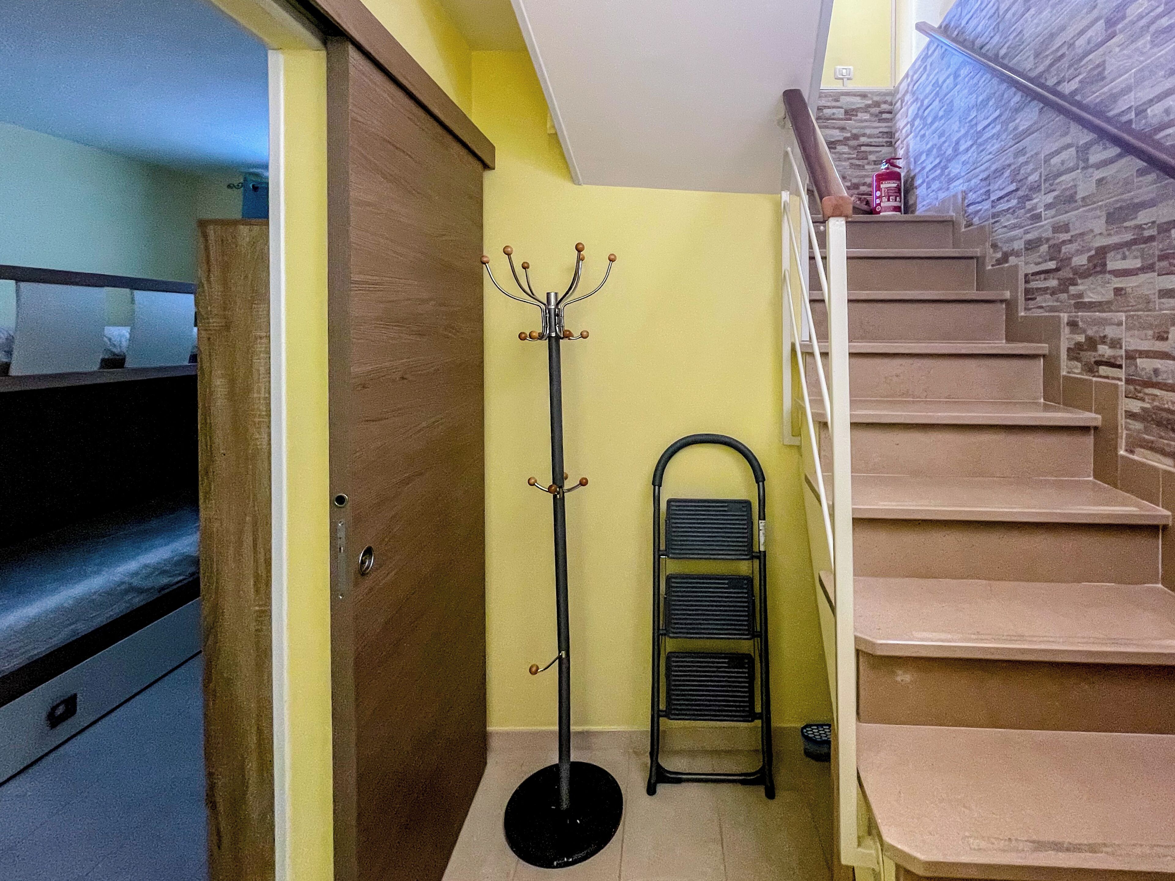 Uma escadaria com corrimão de metal, um porta-roupas e um radiador preto.