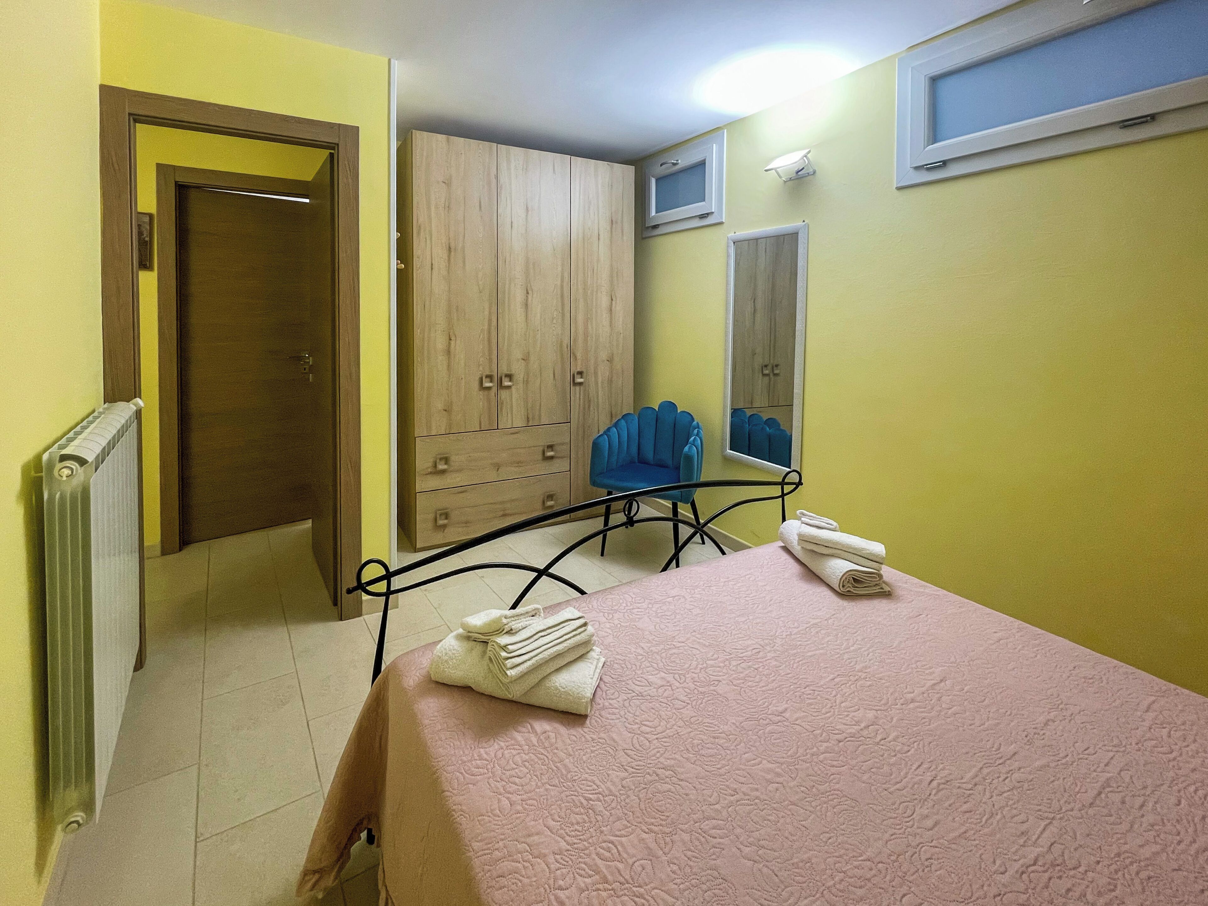 A bedroom with a bed, a chair, a wardrobe, and a radiator.