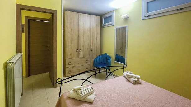 A bedroom with a bed, a chair, a wardrobe, and a radiator. - FranSea House (Otranto)