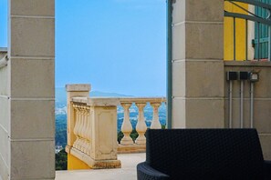 A balcony with a view of a mountain, a chair, and a building with a yellow facade. - Villa Emma with Ocean View (Toulon)