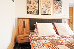A bedroom with a bed, pillows, a nightstand, a wooden wardrobe, and three floral paintings on the wall. - Villa Emma with Ocean View (Toulon)