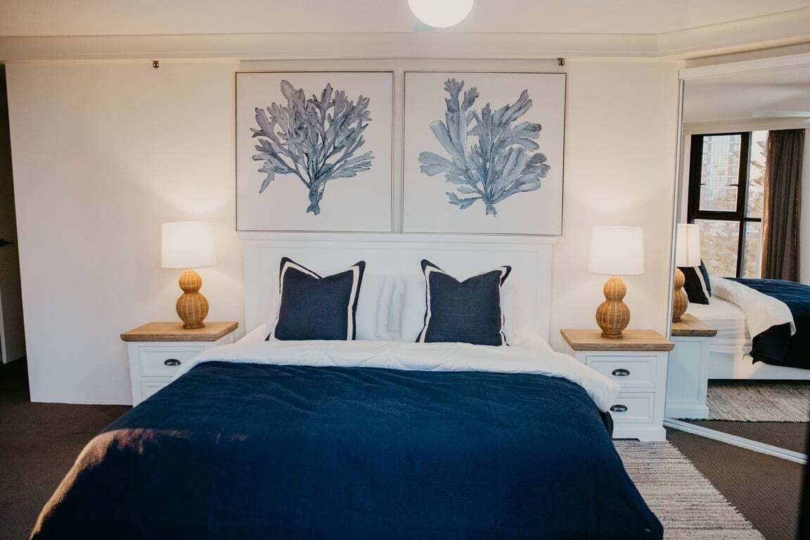 Une chambre d’hôtel avec un grand lit, deux tables de chevet avec des lampes et des œuvres d’art accrochées au mur.