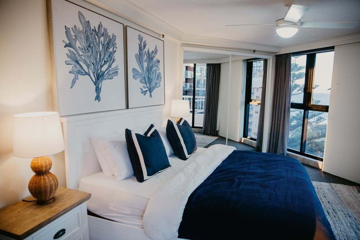 Een hotelkamer met een groot bed, een nachtkastje, een lamp en kunst aan de muur.