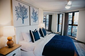 A hotel room with a large bed, a nightstand, a lamp, and artwork on the wall. - Biarritz by the Sea | Resort Days & Ocean Views (Gold Coast)