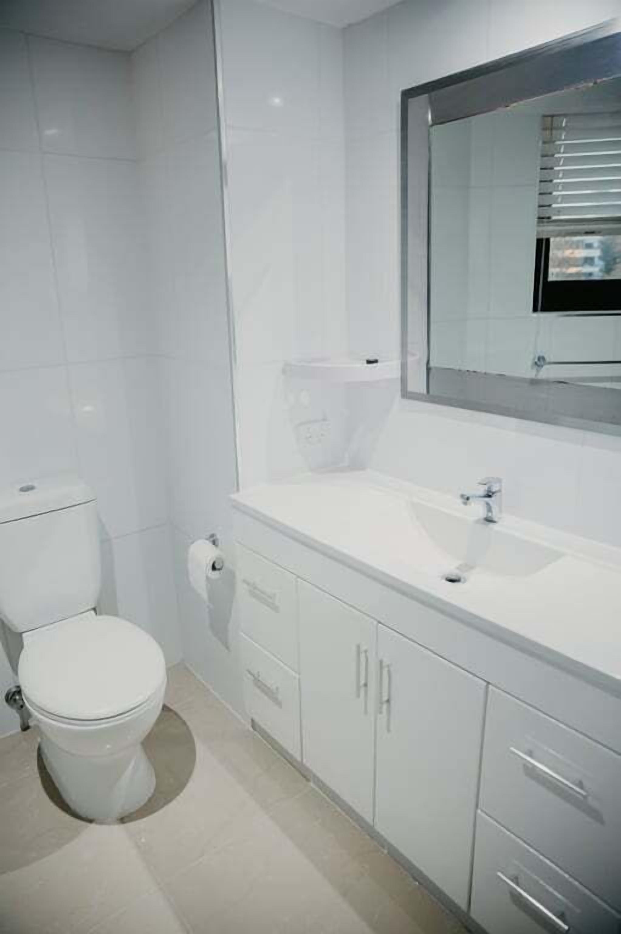 Une salle de bain moderne équipée de toilettes, d’un lavabo et de meubles de rangement.