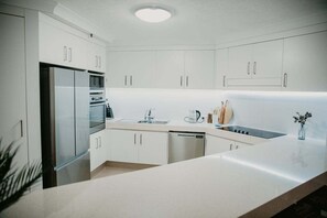 Une cuisine moderne avec des meubles blancs, des appareils en acier inoxydable et un plan de travail en marbre.