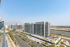 A modern high-rise building with multiple balconies and a rooftop terrace. - Stylish Studio Retreat with Balcony Overlooking Serene Community Views (Dubai)