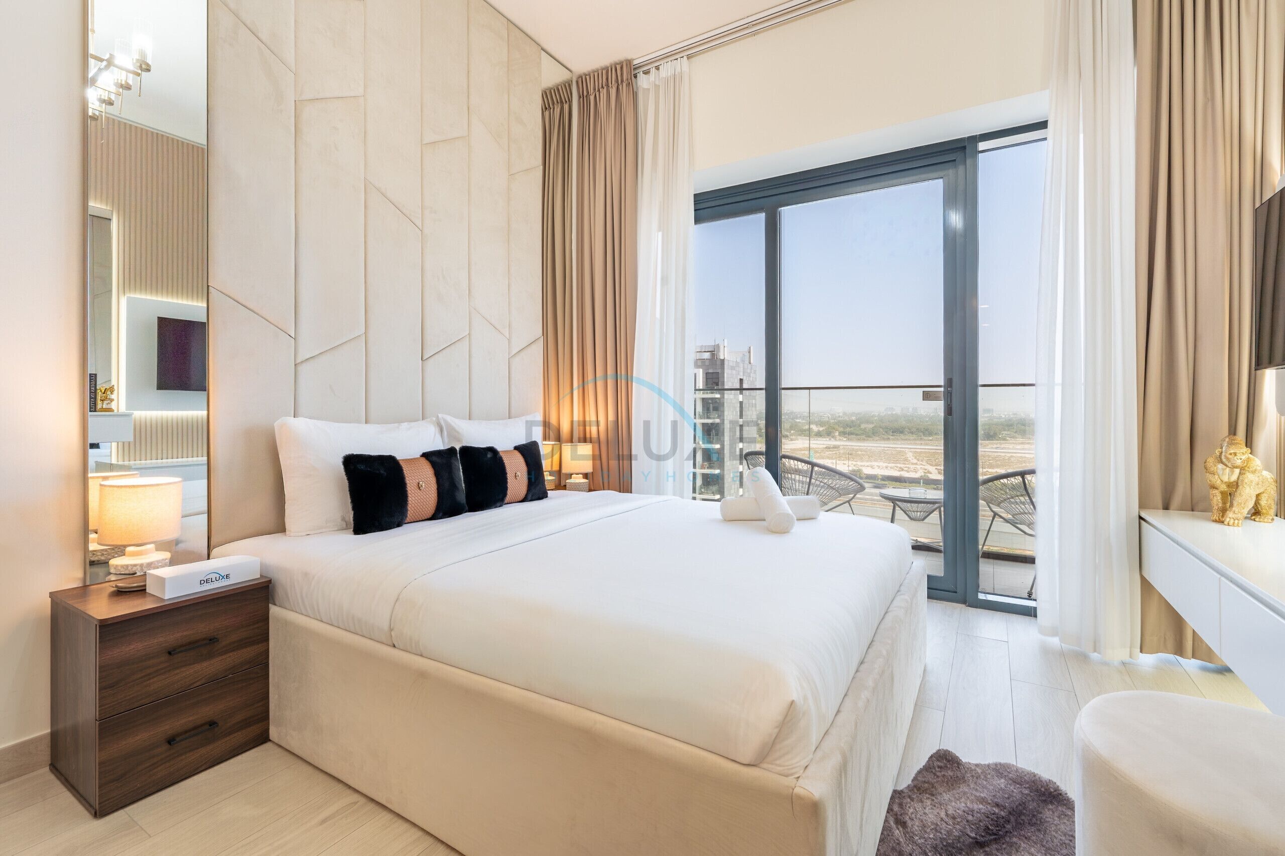 Een moderne hotelkamer met een groot bed, een bureau en een balkon met uitzicht op de stad.