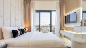 Ett hotellrum med en stor säng, en tv, ett skrivbord och utsikt över stranden.