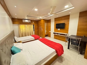 Habitación de hotel con dos camas, un escritorio, una silla, un televisor y un ventilador de techo.